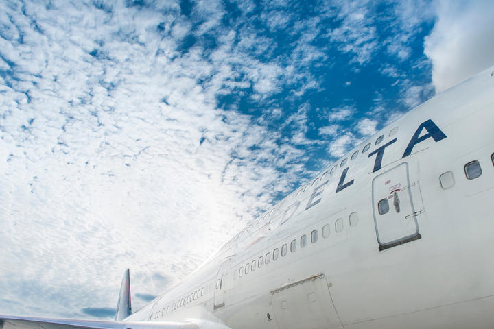 Close up of Delta aircraft with blue skies and clouds