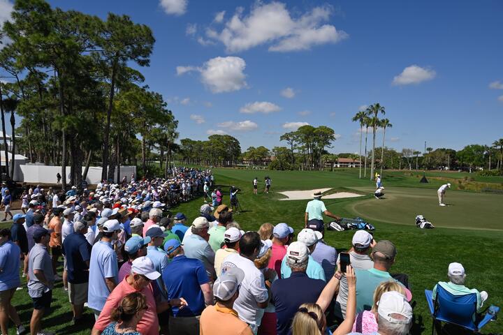 Fans surround a golf green while attending a PGA Tour event.