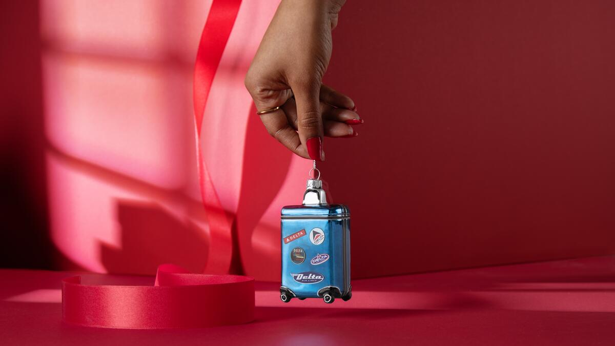 Roll into the holidays with our glass, Heritage Delta Suitcase ornament. This ornament is guaranteed to standout on your tree with its blue hues and miniature Heritage patches.  